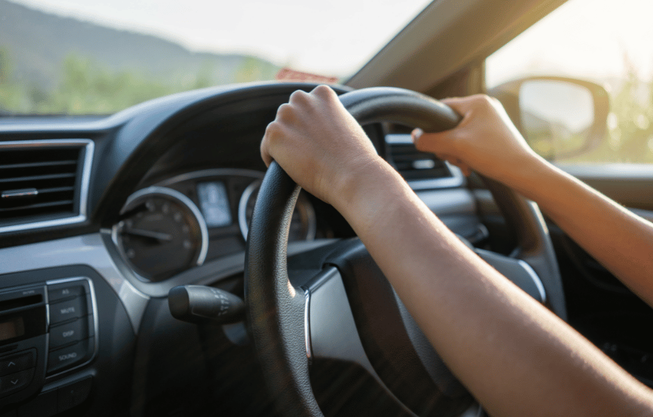 person driving car with hands on the steering wheel