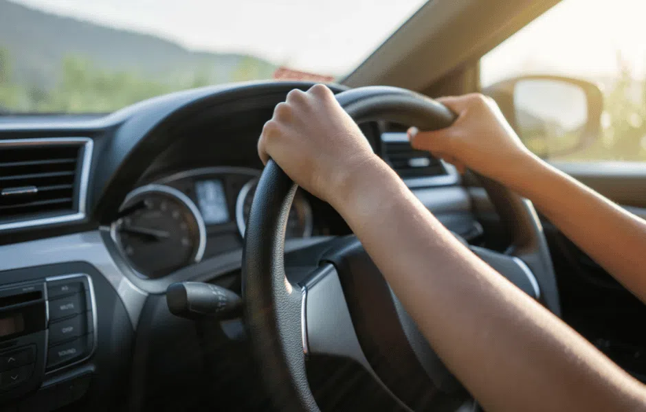 person driving car with hands on the steering wheel